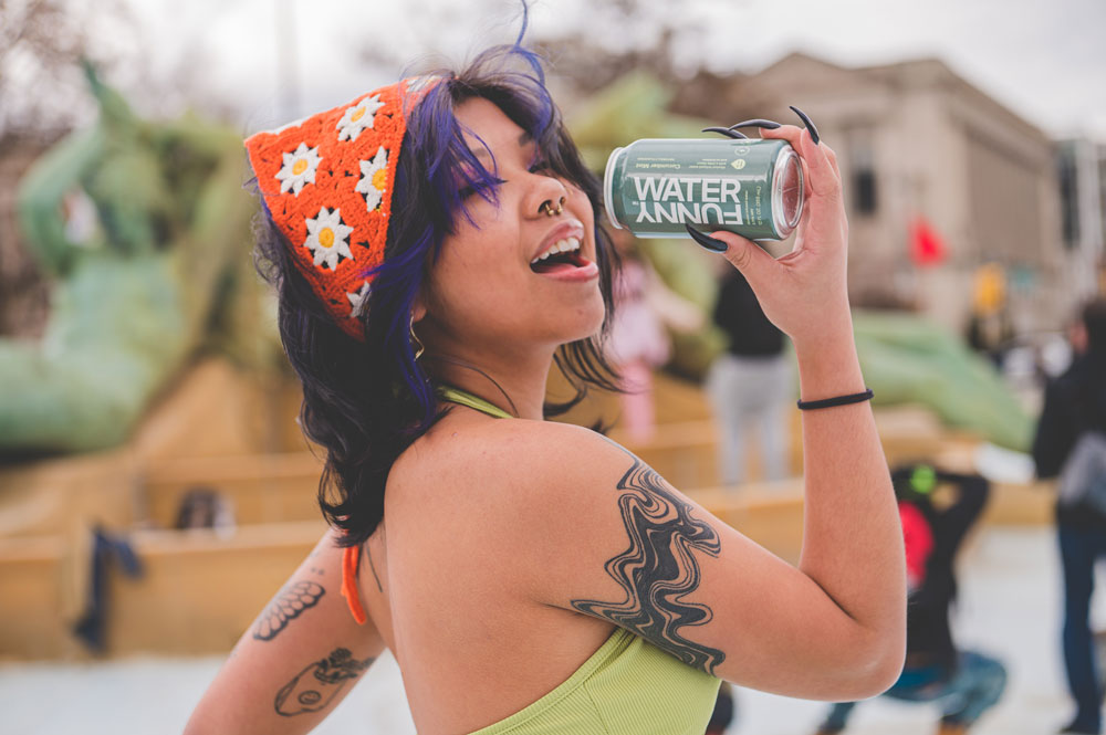 Woman posing while drinking a can of Funny Water